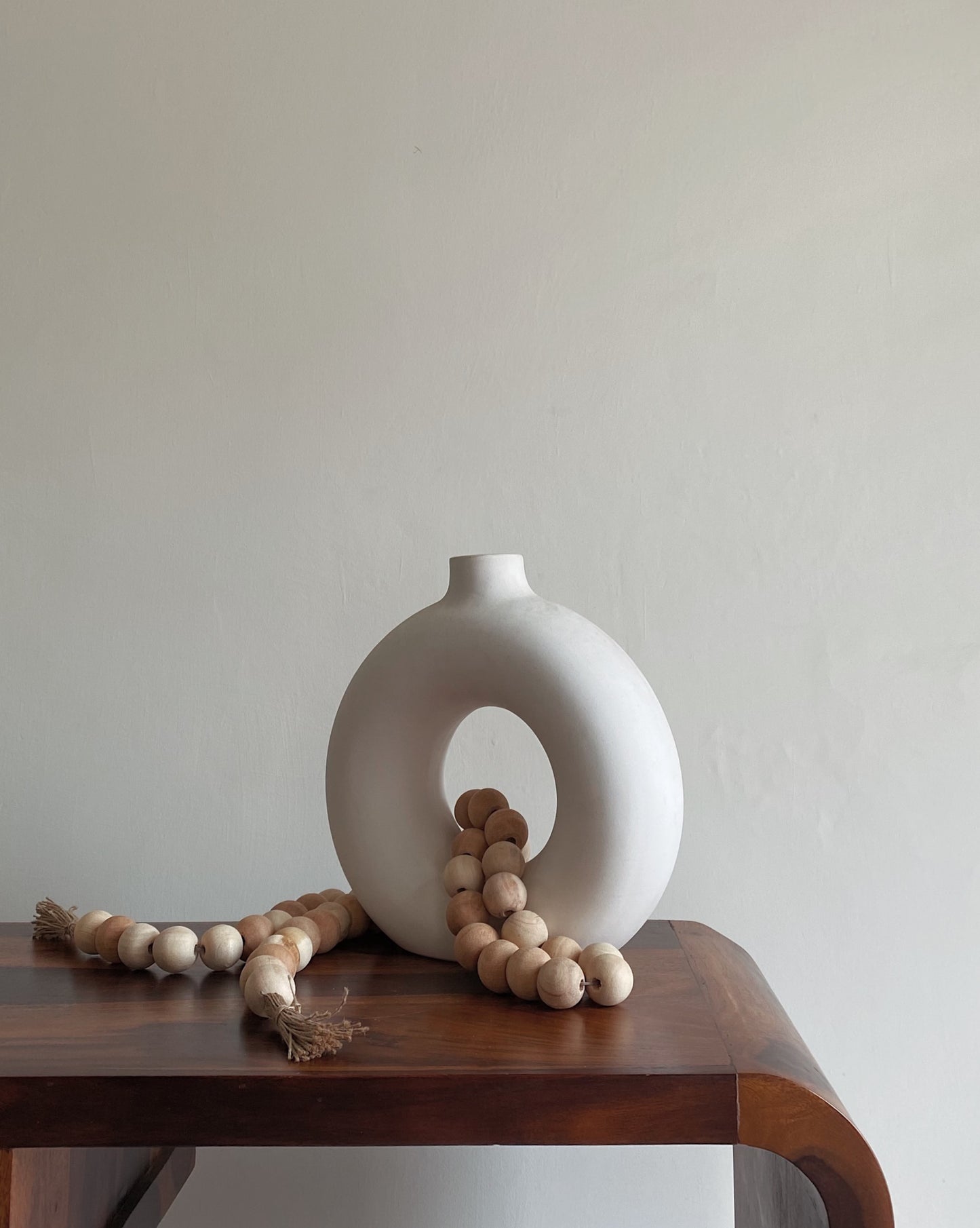 Wooden beads layered over a ceramic vase